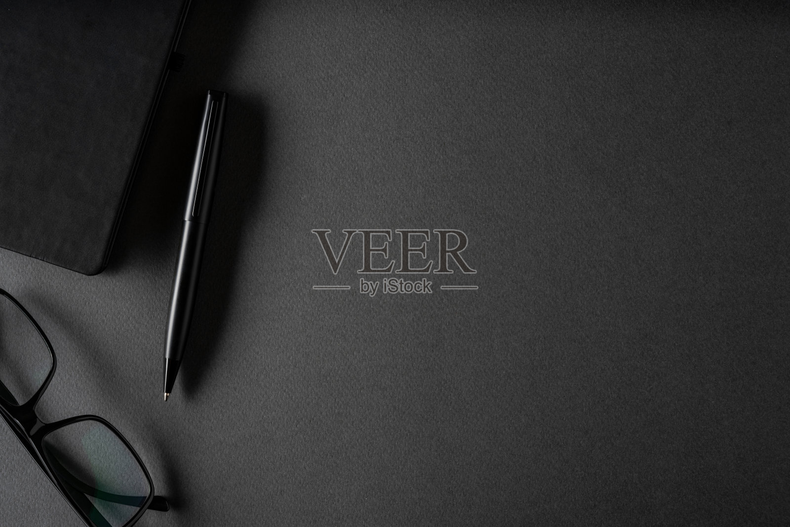 俯视图,圆珠笔,眼镜和记事本躺在深灰色的桌子上照片摄影图片