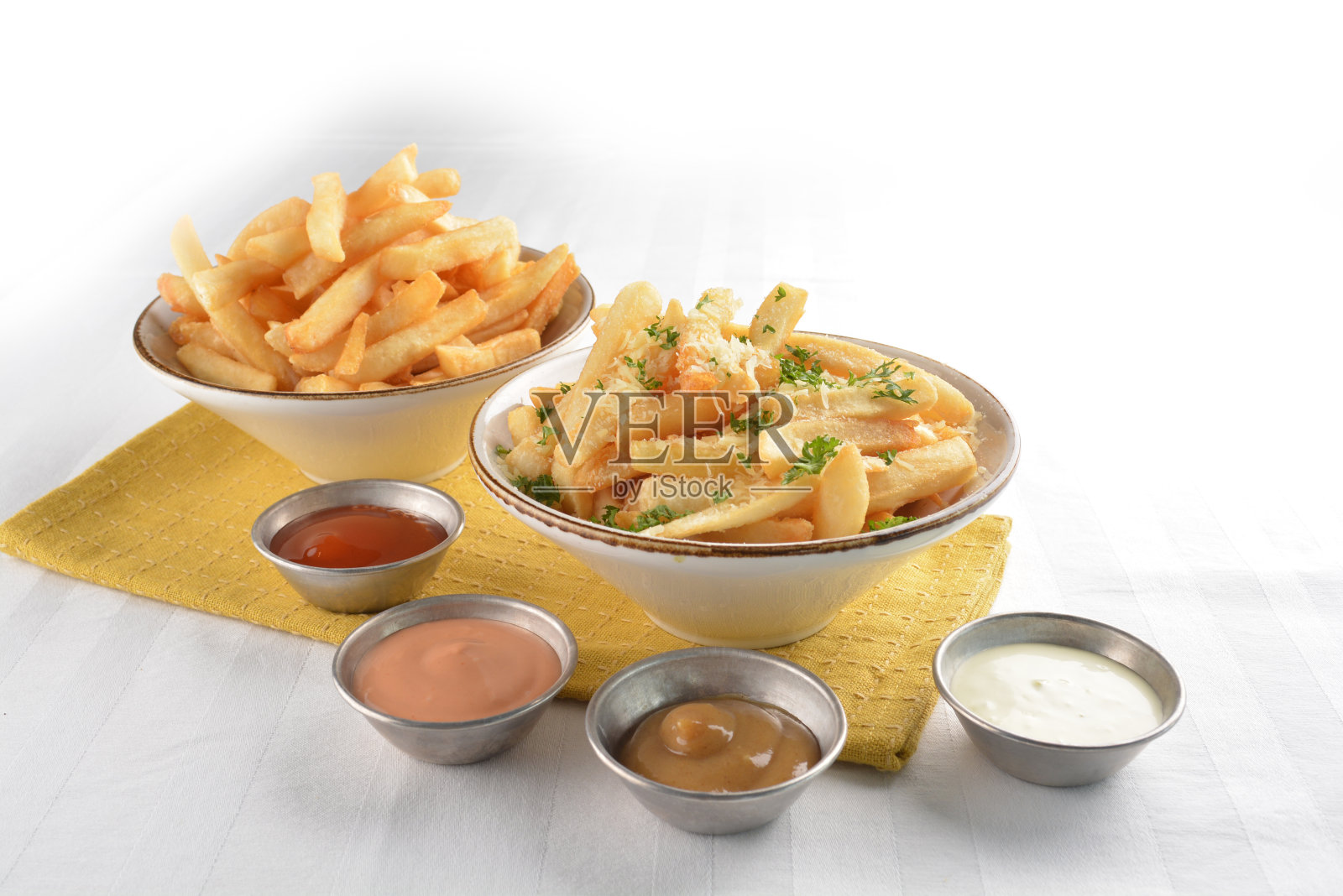 白色桌子上的盘子里装着金黄色的油炸法式薯条,配帕尔马干酪酱。西式咖啡馆小吃店清真快餐开胃菜菜单照片摄影图片