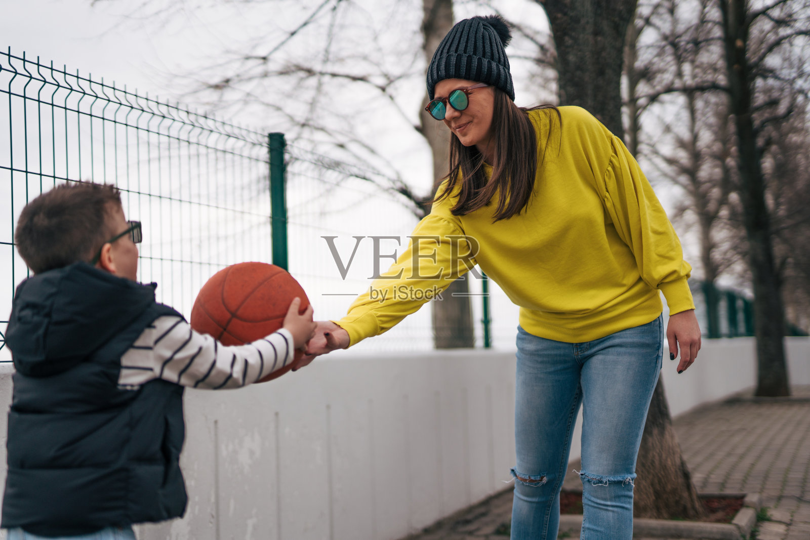 母亲和儿子一起在户外打篮球。照片摄影图片