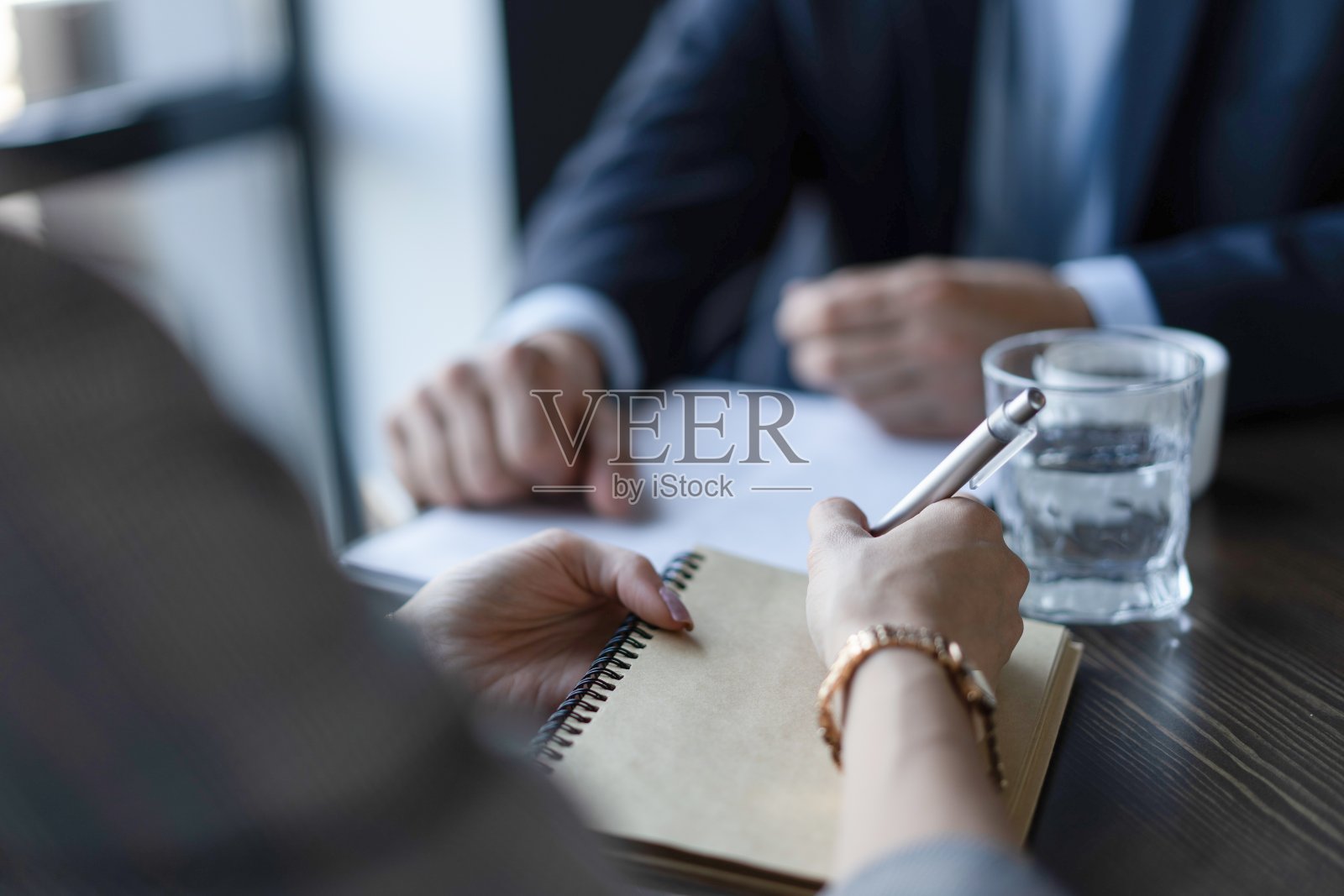 近距离看坐在桌子旁的白人女人和男人的手。指导老师面试新候选人照片摄影图片