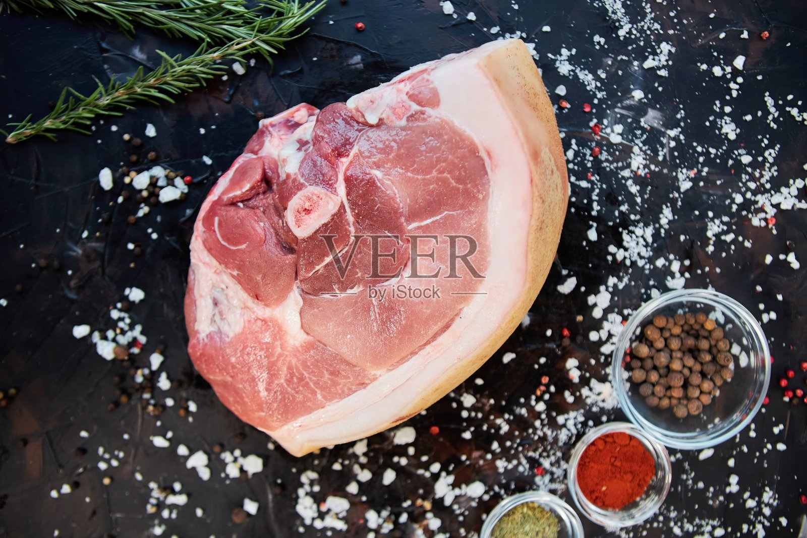 生肉躺在被香料包围的深色背景上。肉类生产。照片摄影图片