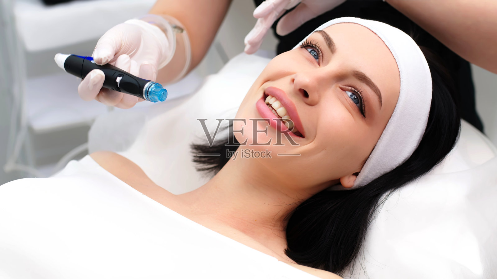 抗衰老、护肤、洁面。美容师在美容诊所里给妇女做面部护理。照片摄影图片