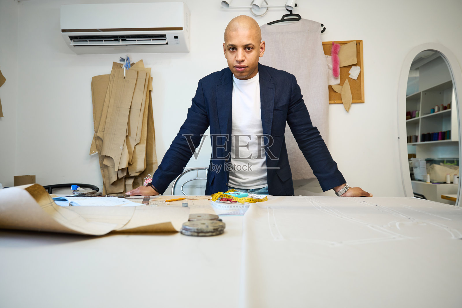 严肃的服装师在工作室裁剪材料前对着镜头摆姿势照片摄影图片