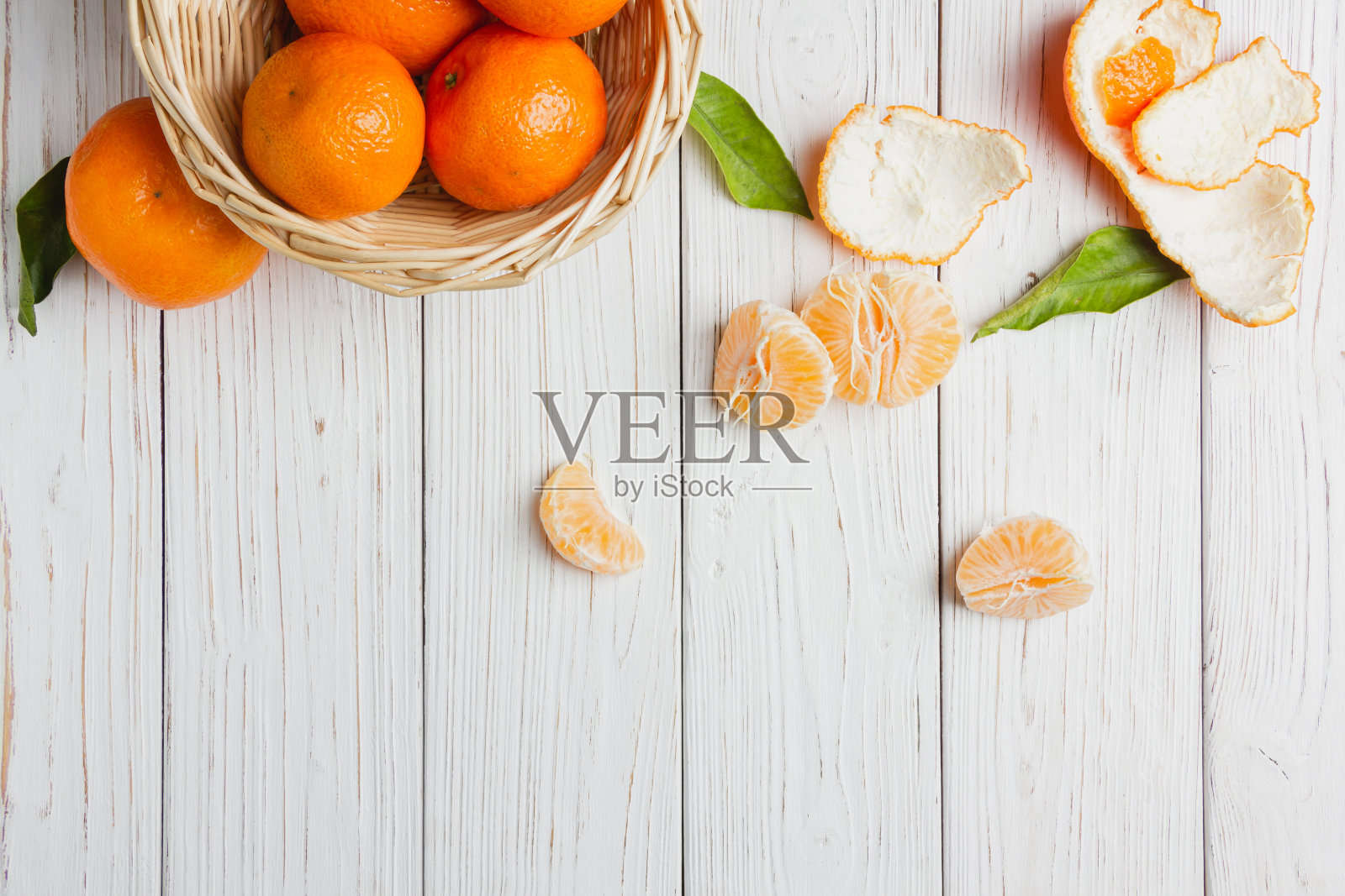 白色木桌上的稻草篮子里装着橘子。照片摄影图片