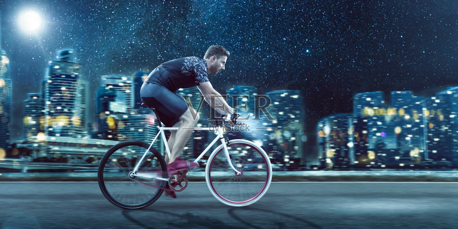 晚上在城市天际线前骑自行车的人照片摄影图片