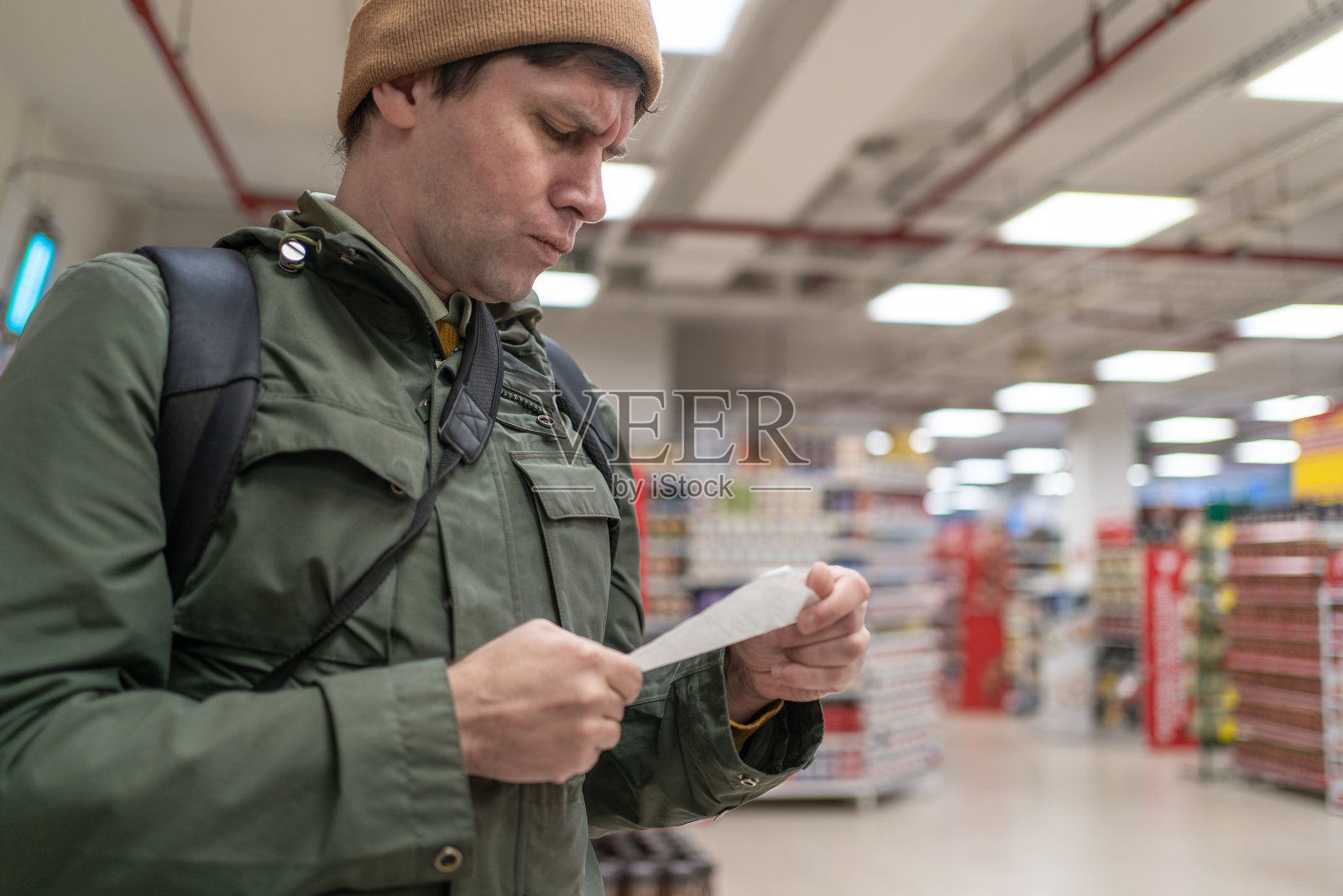 一位顾客拿着纸质收据和超市货架上的价格比较照片摄影图片