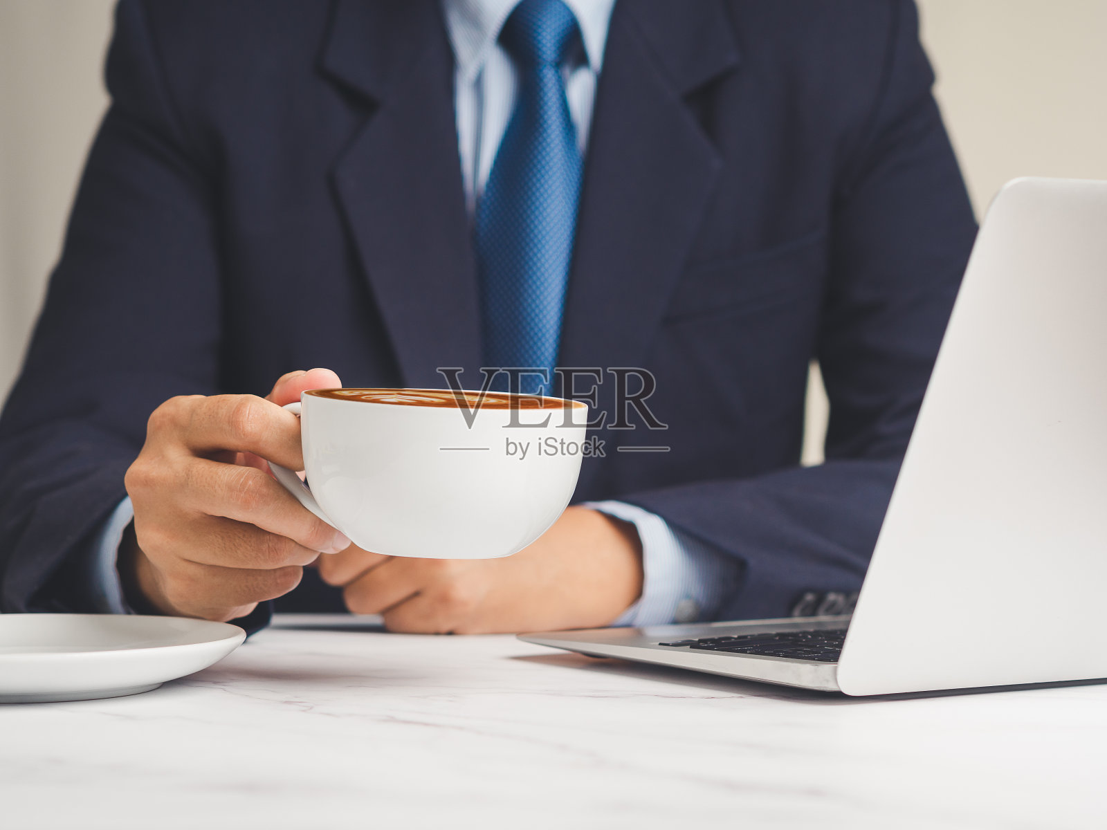在办公桌前工作的商人端着一杯咖啡。照片摄影图片