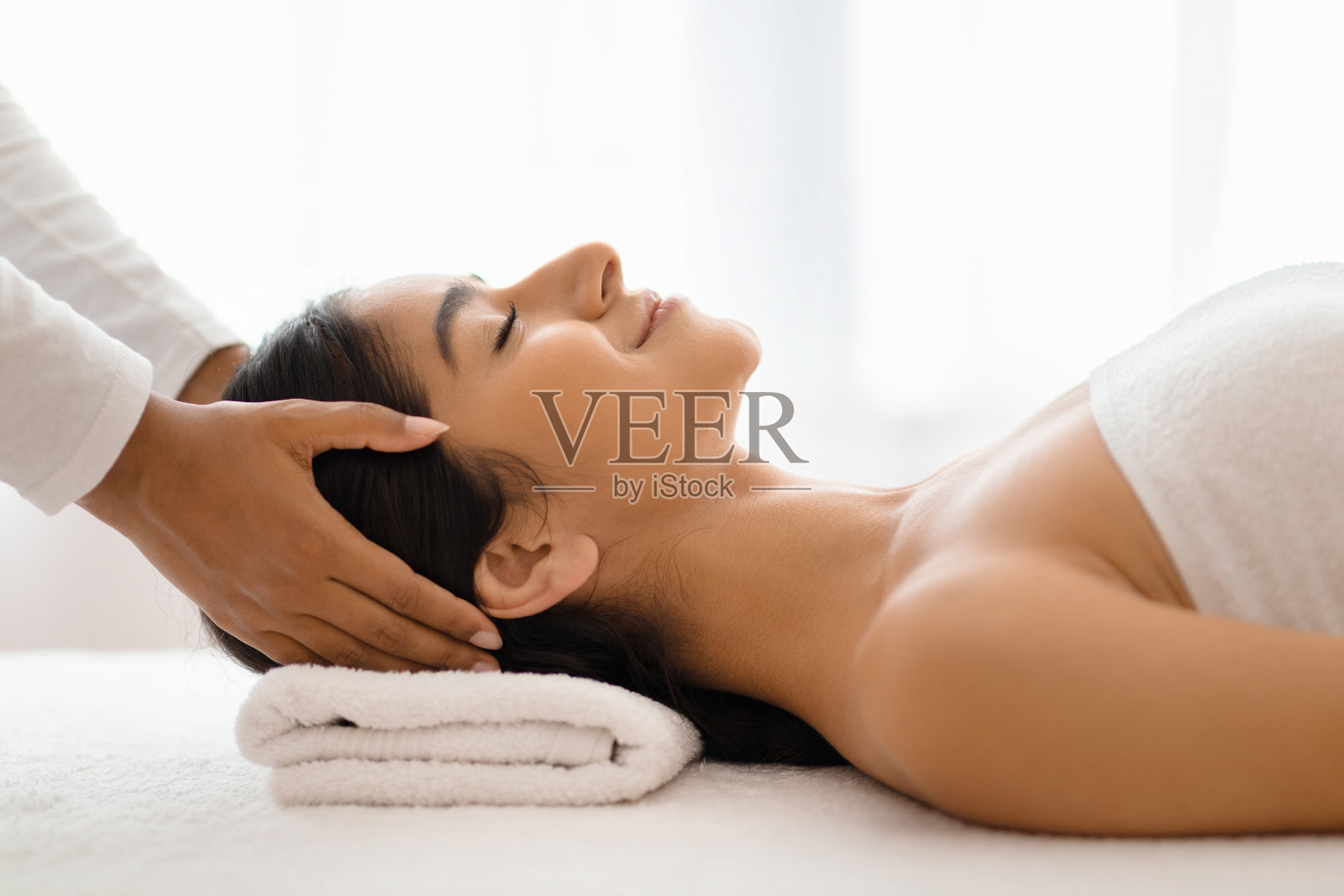 按摩师为年轻美丽的印度女士做放松的头部按摩照片摄影图片