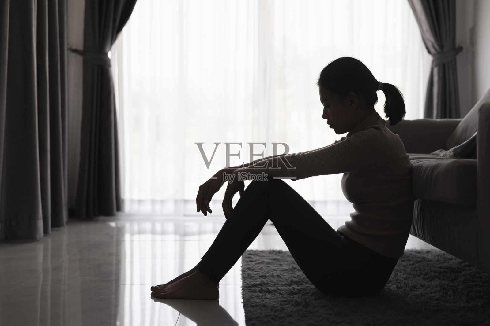 黑暗房间里独坐的抑郁女性剪影照片摄影图片