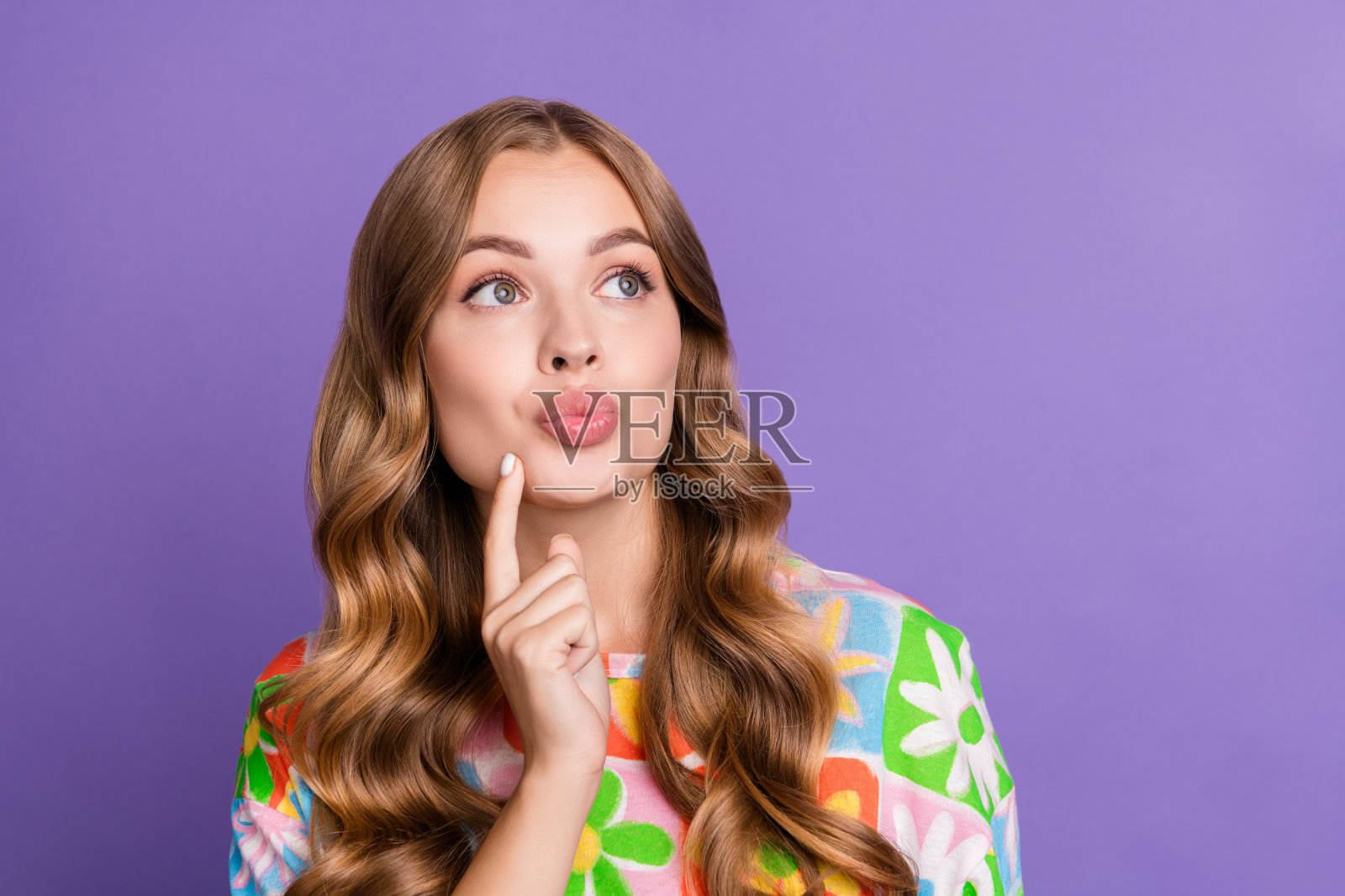 年轻漂亮的女朋友的肖像想着送给她的礼物,她的男朋友触摸脸颊丰满的嘴唇孤立在紫色的背景照片摄影图片