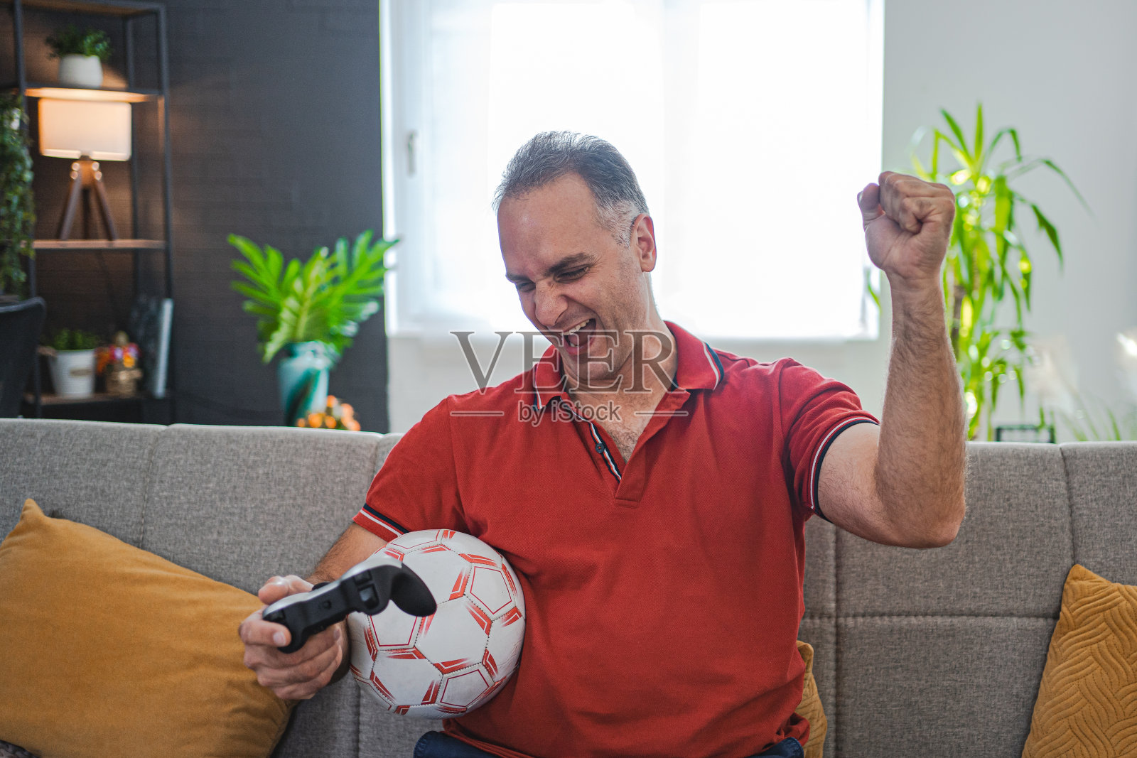 兴奋的中年男子在家玩足球电子游戏照片摄影图片