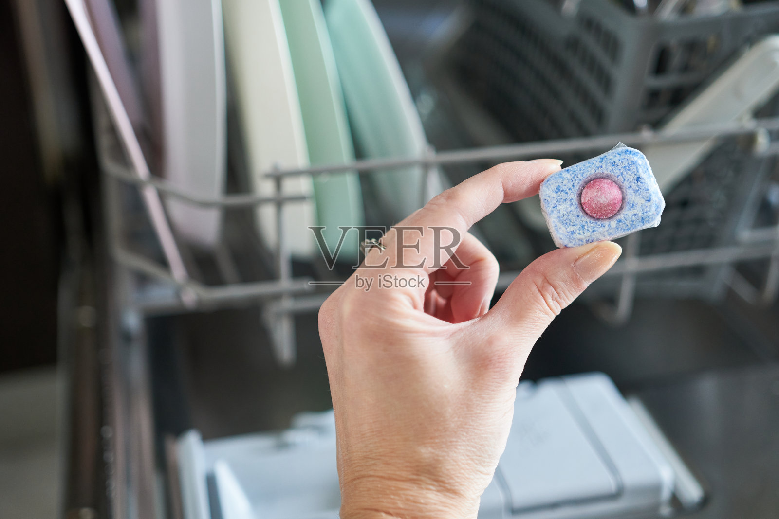 一个女人手拿洗碗机清洁剂的特写。照片摄影图片