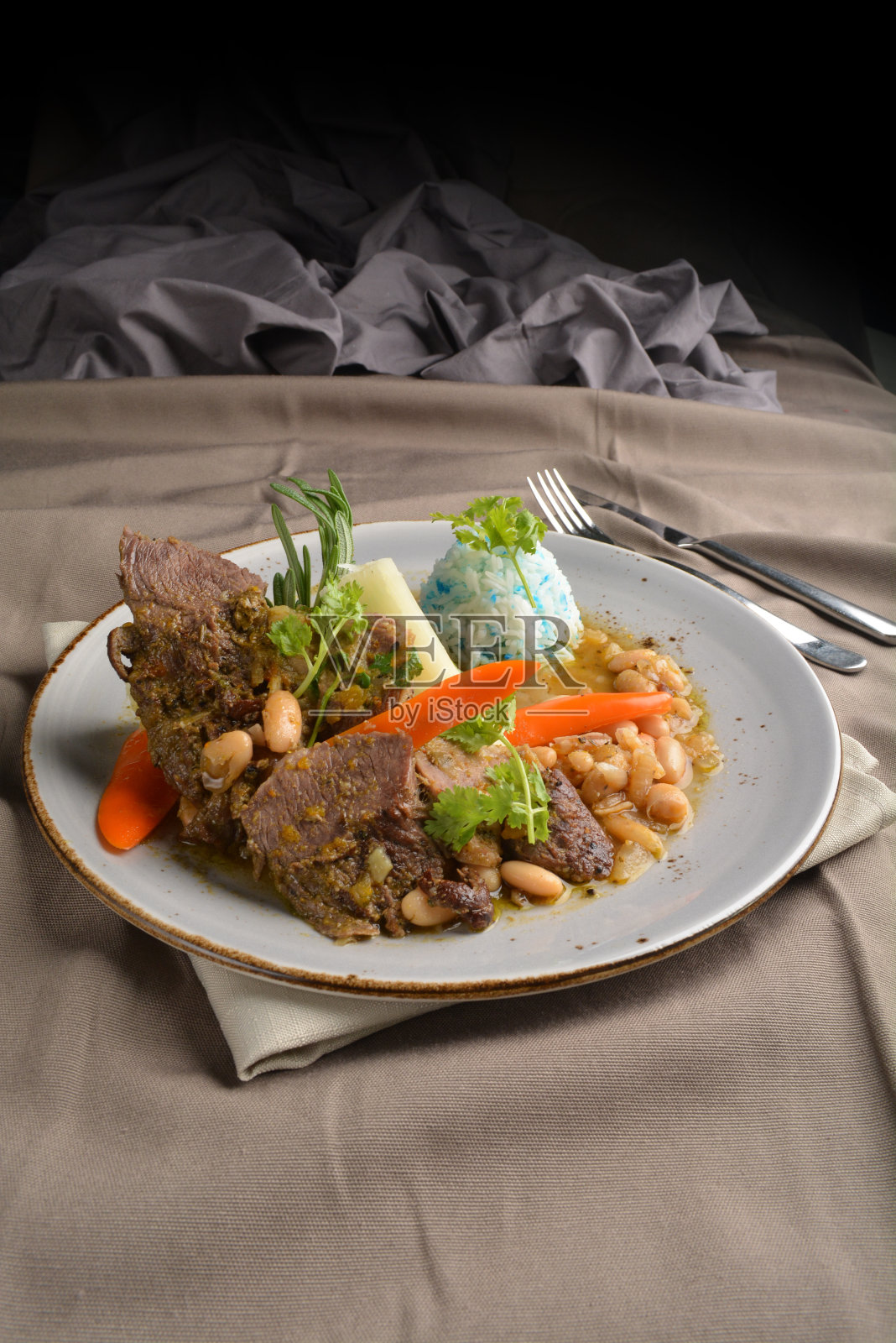 西餐厅秘鲁料理咖啡馆清真菜单,焗豆炖牛排和蓝豌豆蝴蝶花米饭盘,棕色布桌照片摄影图片