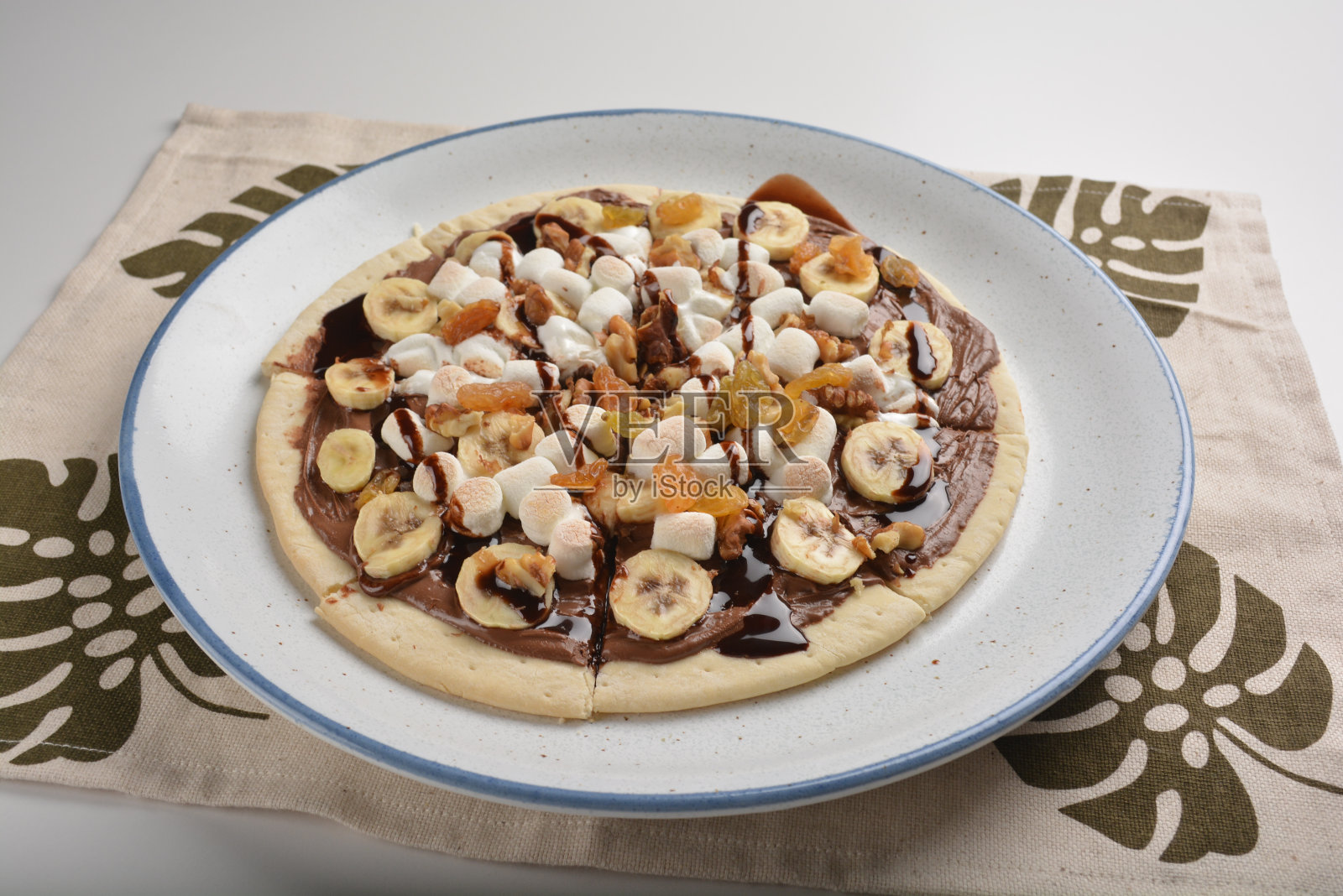 厨师烤巧克力香蕉披萨与棉花糖和干葡萄水果甜点为孩子们在盘子白色的桌子酒店高级餐厅西方清真咖啡厅菜单照片摄影图片