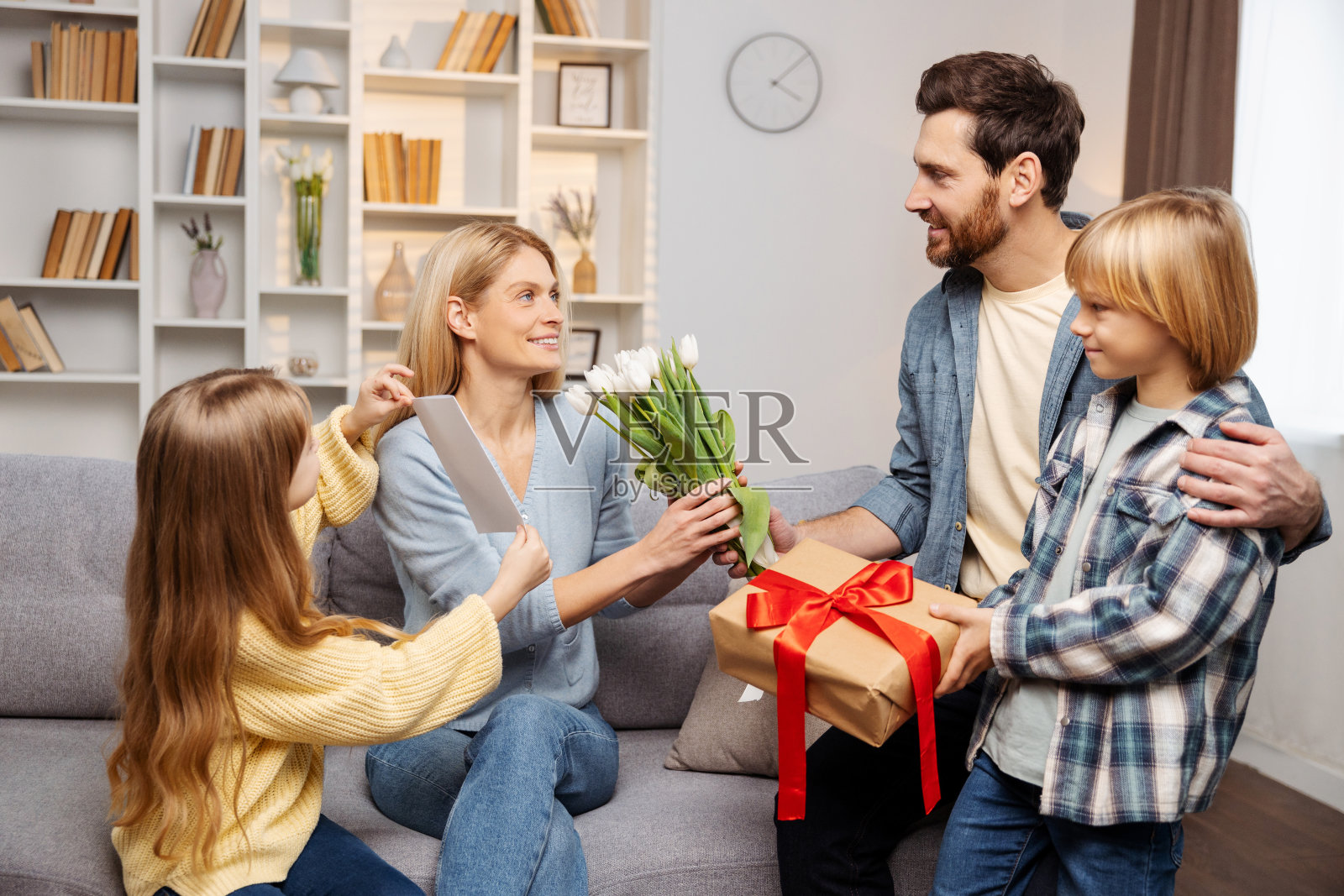 在室内庆祝母亲节:父亲、儿子和女儿在客厅里给母亲送礼物照片摄影图片