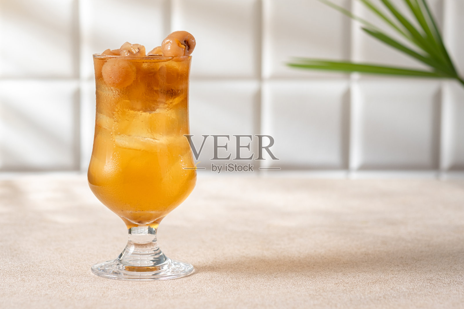 一杯冰凉的桂圆汁加冰,餐桌上的窗户点缀着晚霞。照片摄影图片