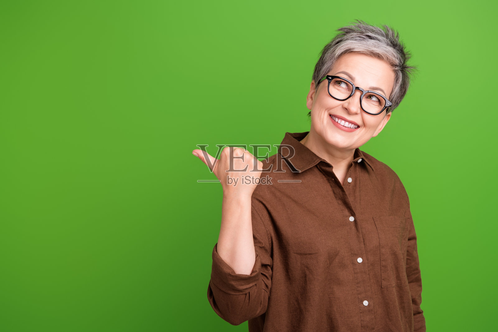一个穿着棕色衣服,戴着眼镜,笑容满面的人的肖像,在绿色的背景上看着销售的空白空间照片摄影图片