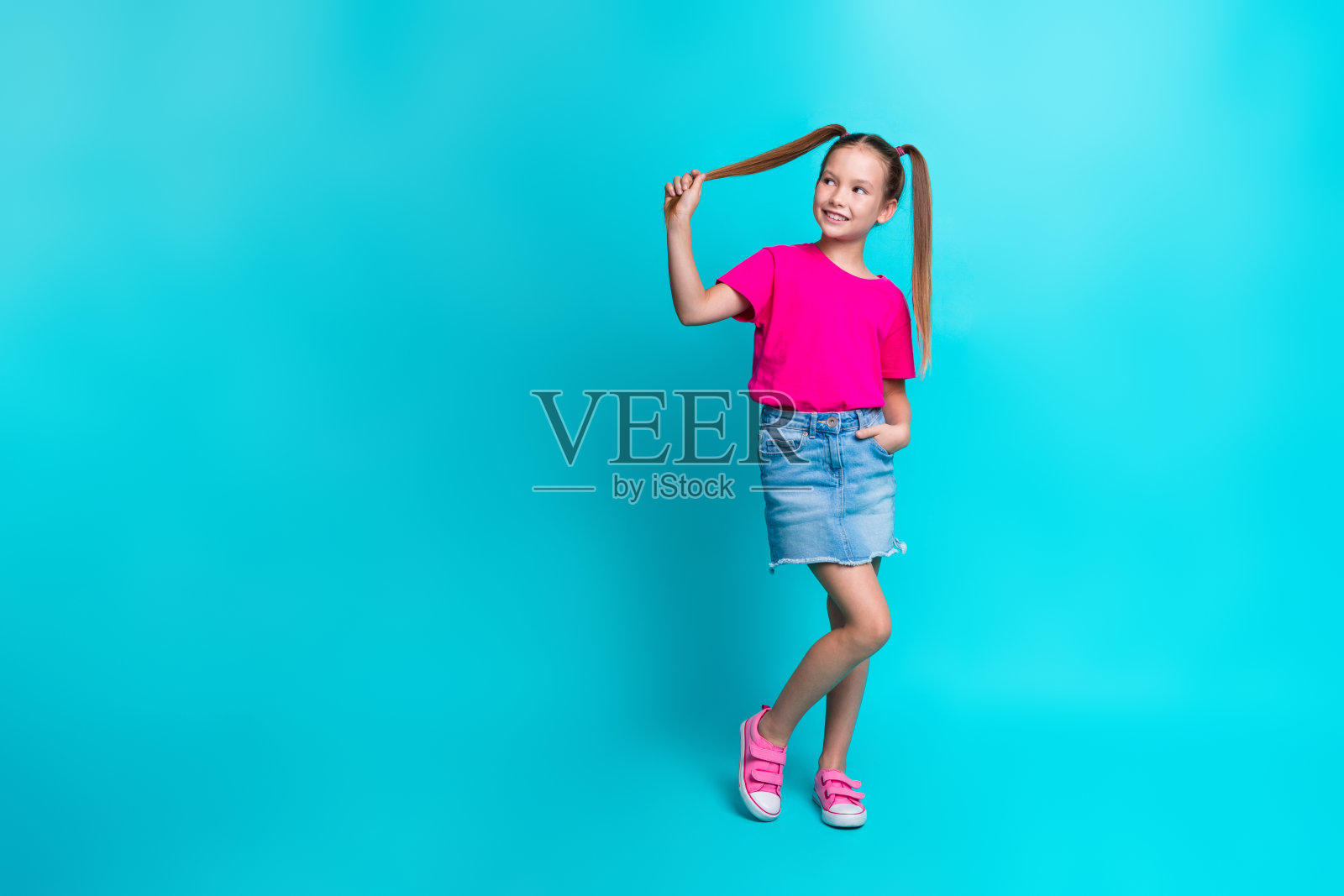 可爱华丽的女孩穿着时髦的粉红色衣服的全身照片,查找特别优惠新闻,在青色背景上孤立的空白空间照片摄影图片