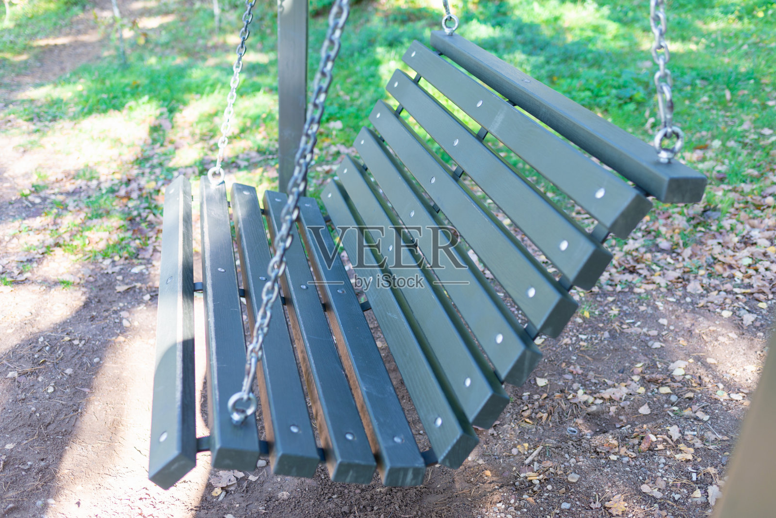 空荡的秋千,树木中间的木桌和长椅,秋天的公园,阳光明媚的一天。照片摄影图片