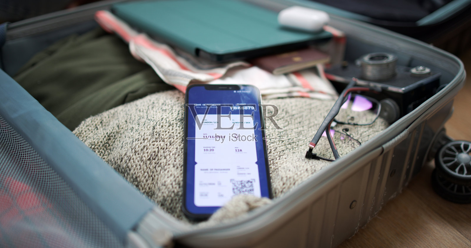 智能手机上的数字登机应用程序,衣服和行李放在行李箱里照片摄影图片