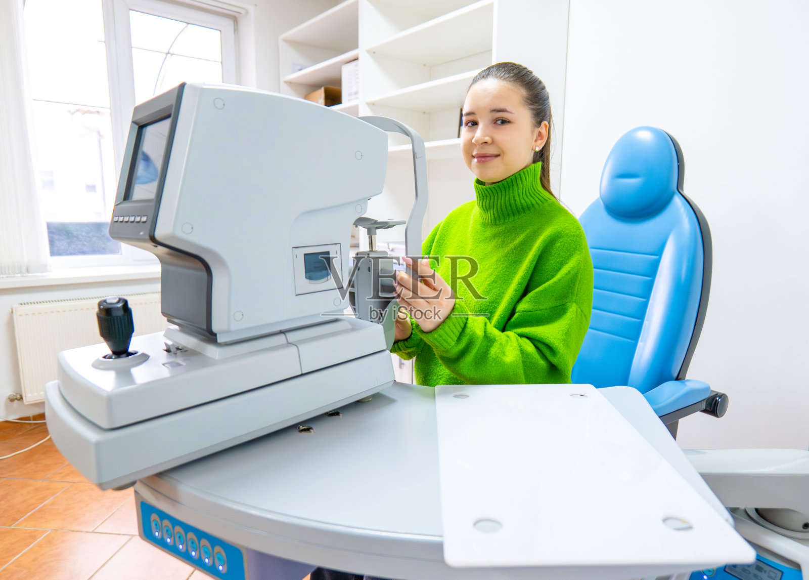 一个穿绿色毛衣的女人坐在机器前的椅子上照片摄影图片