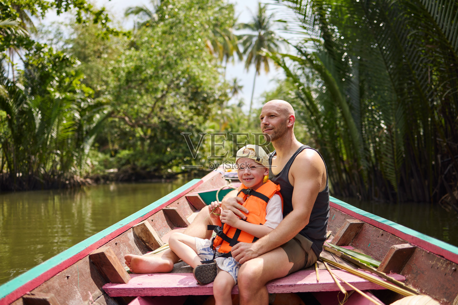 一位父亲和他的儿子坐在一艘长尾船上,在运河上旅行照片摄影图片