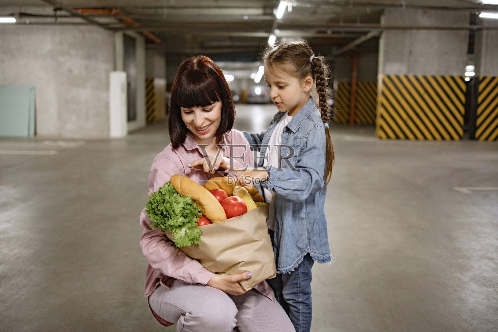 母亲带着学前班的女儿,手里拿着纸袋和蔬菜照片摄影图片