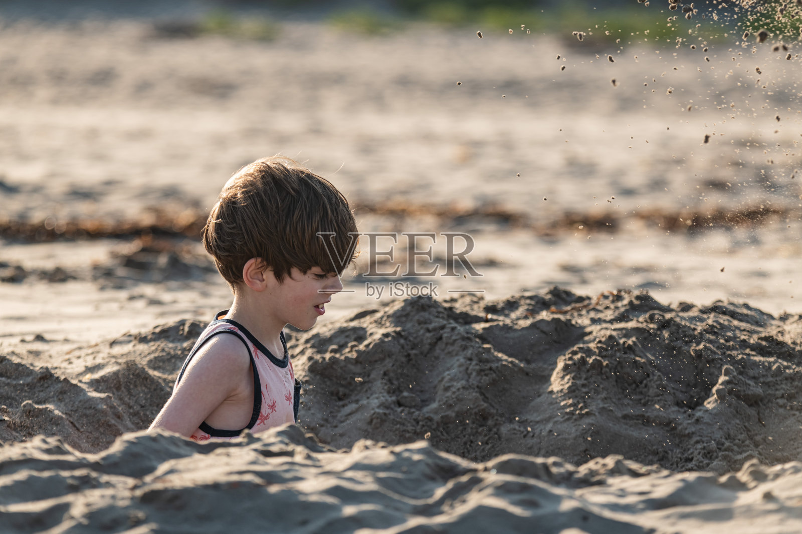 男孩在海滩挖土照片摄影图片