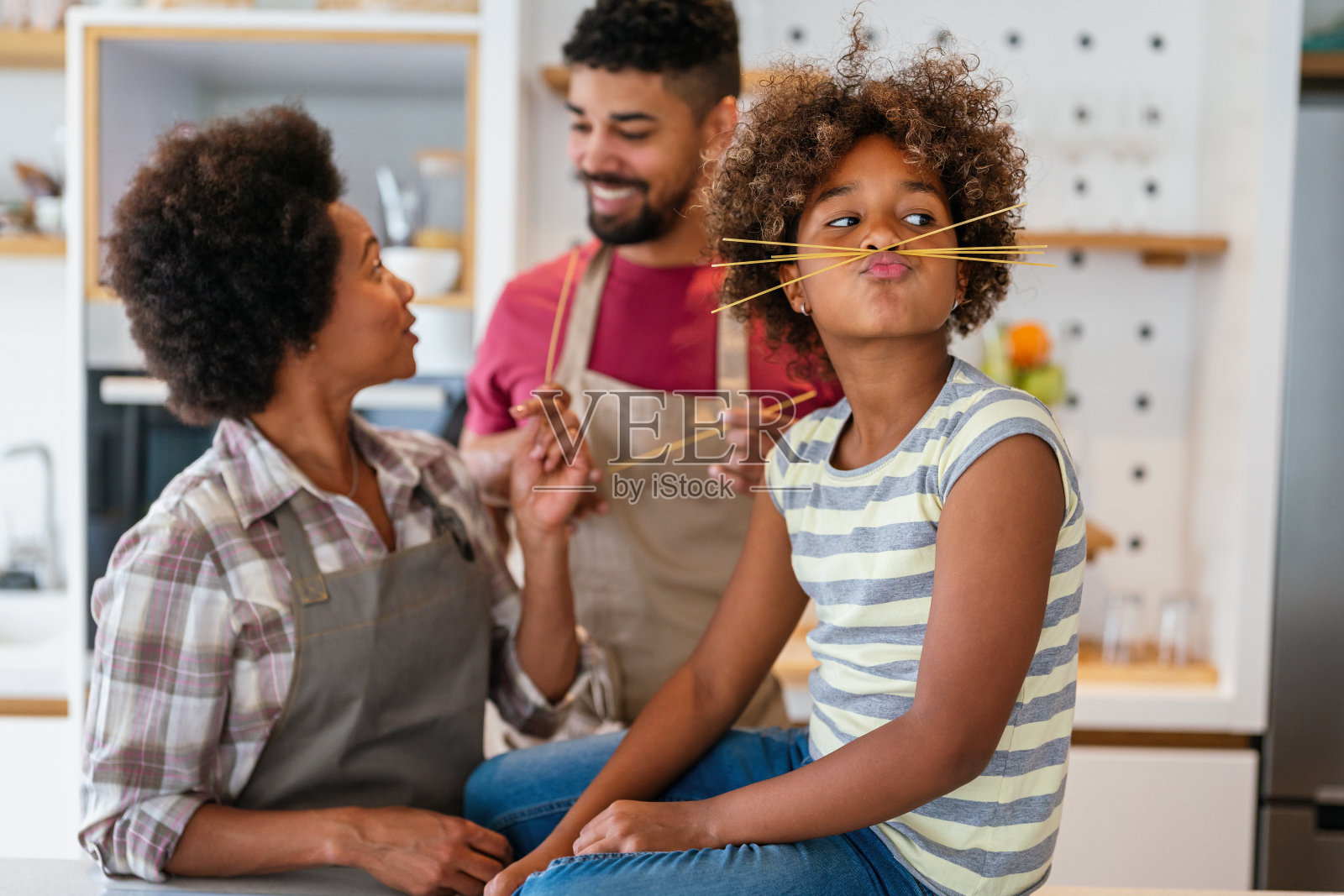 快乐微笑的非裔美国父母享受周末与孩子在厨房玩耍。家庭观照片摄影图片