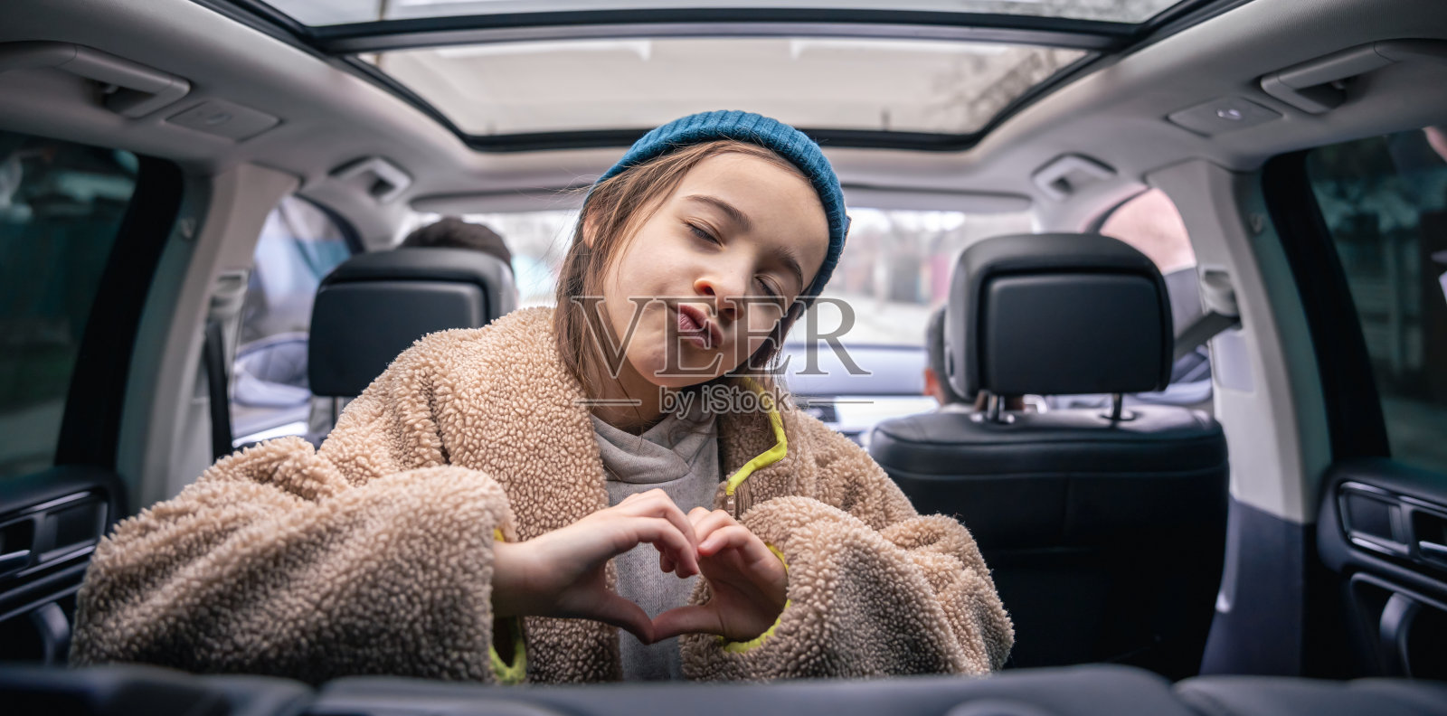 有趣的小女孩在汽车后座上摆姿势,在车里玩耍。照片摄影图片