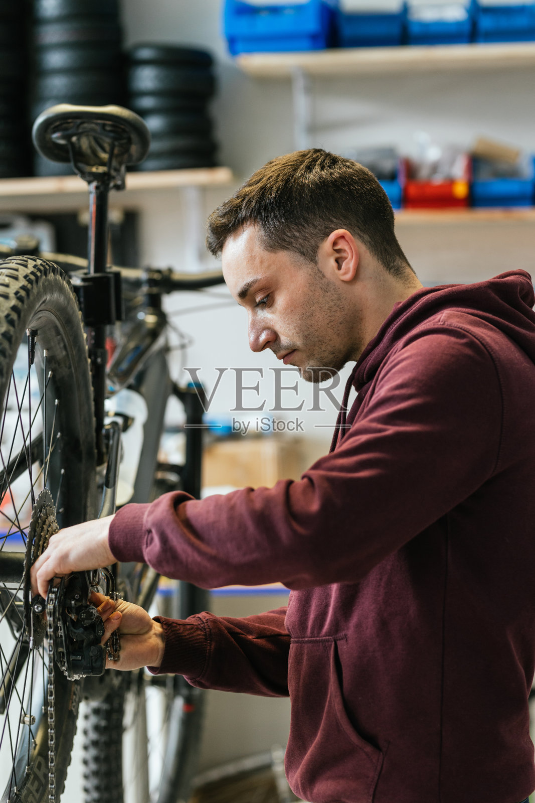 一个自行车修理工的手在山地车的后变速器上换链条的垂直图像。照片摄影图片