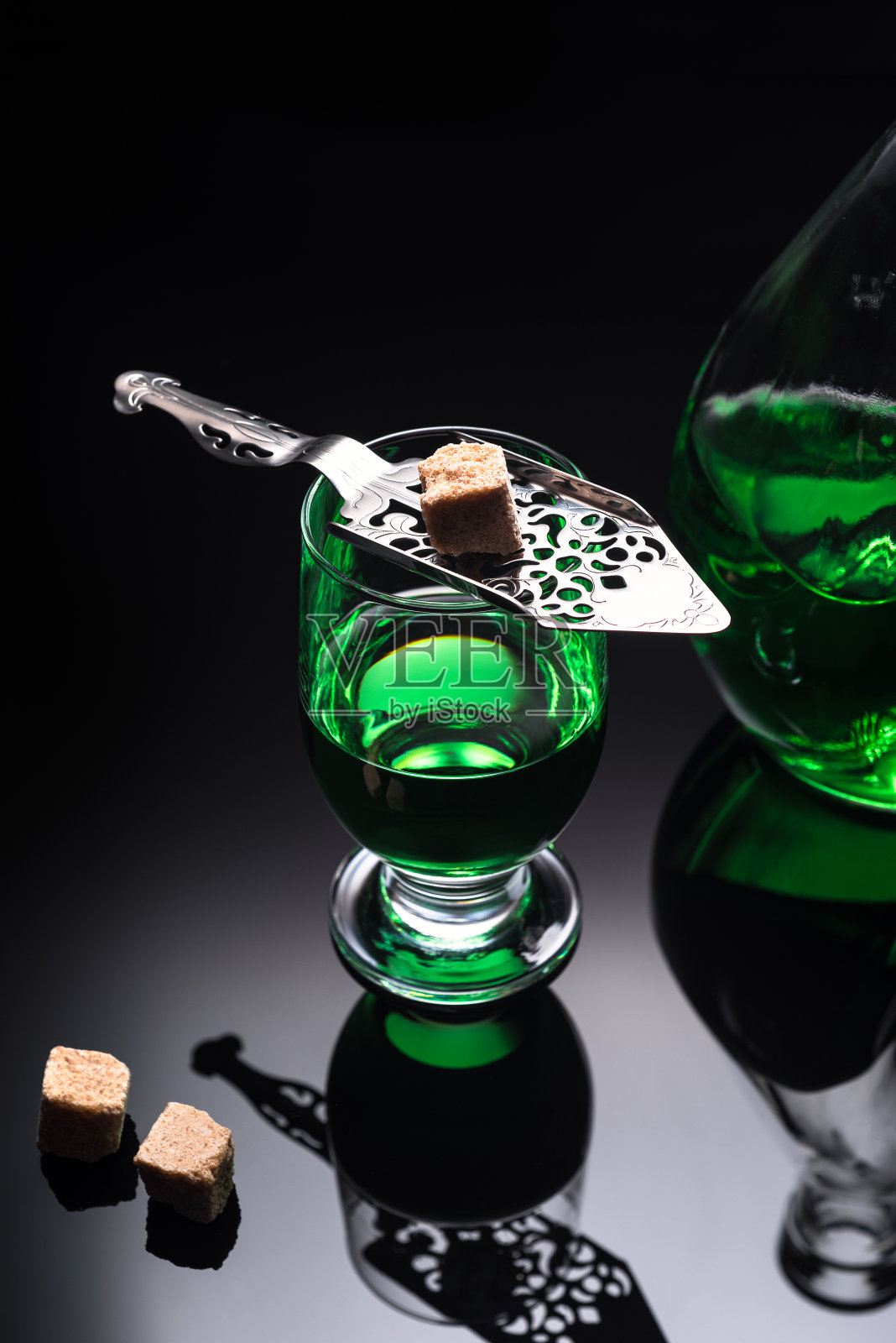 一杯苦艾酒,在深色背景上加一块蔗糖。照片摄影图片