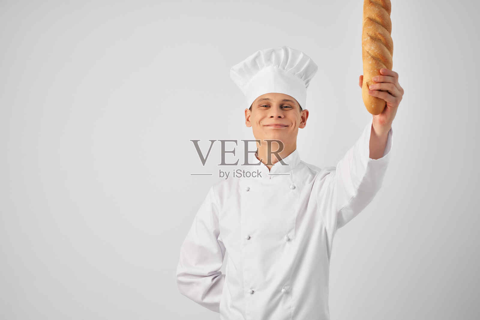 一个穿着厨师服,手里拿着法棍的男人在烘烤新鲜食物照片摄影图片