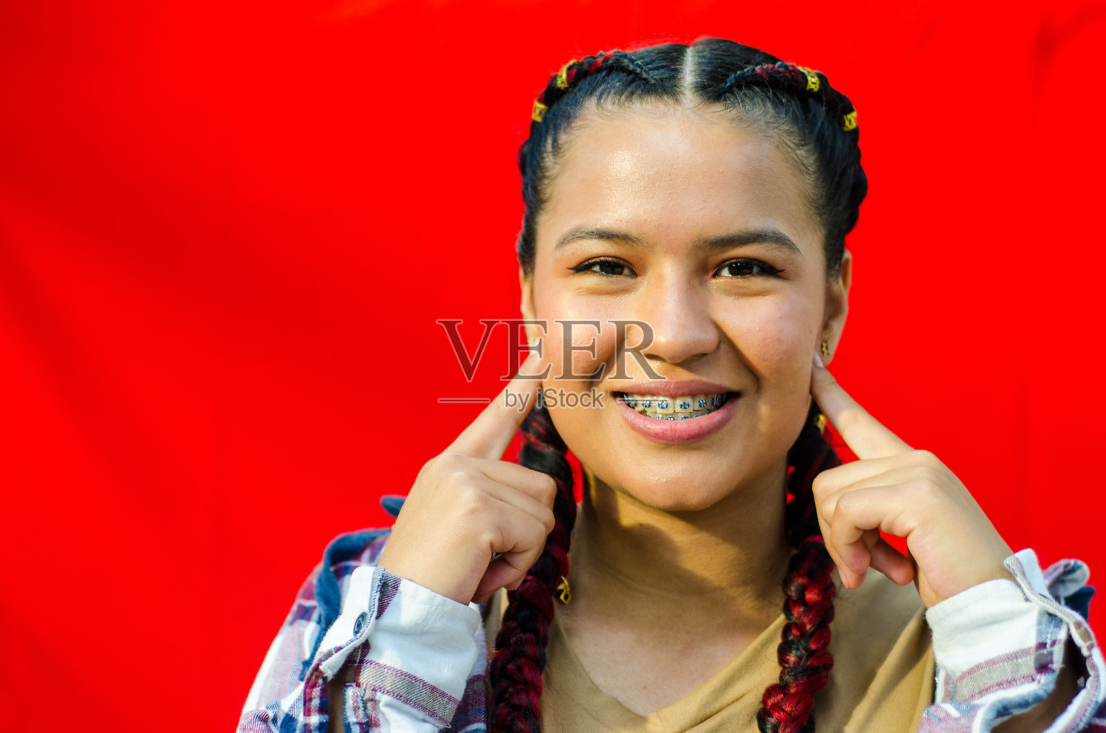 美丽的年轻女子的肖像与辫子在红色的背景照片摄影图片