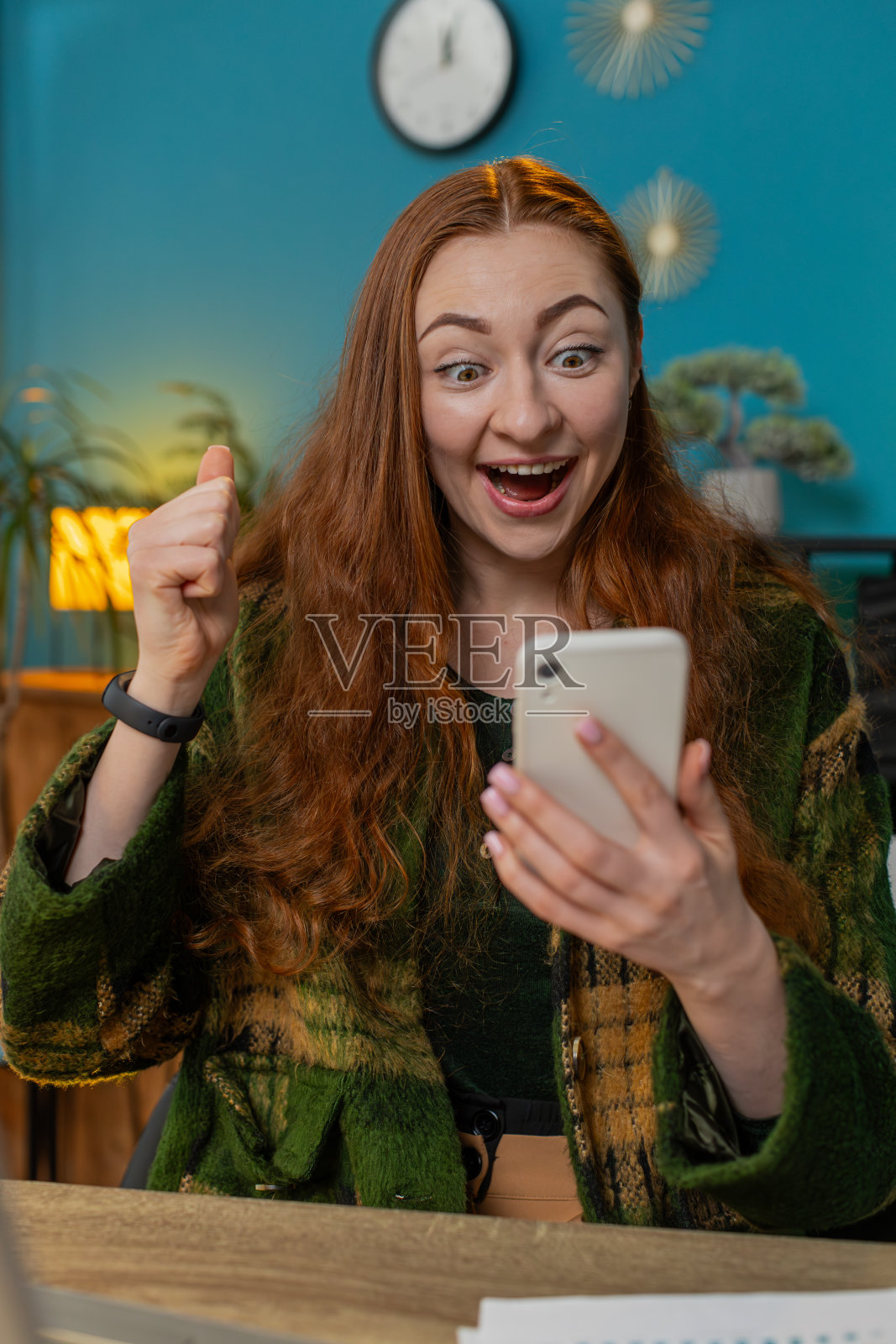 女人在家里用智能手机庆祝成功,胜利,玩网络游戏,好消息照片摄影图片