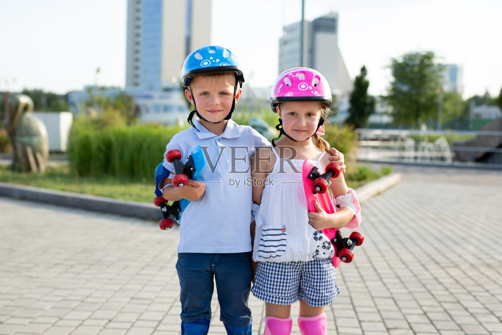 一个男孩和一个女孩在公园里穿着溜冰鞋的肖像。照片摄影图片