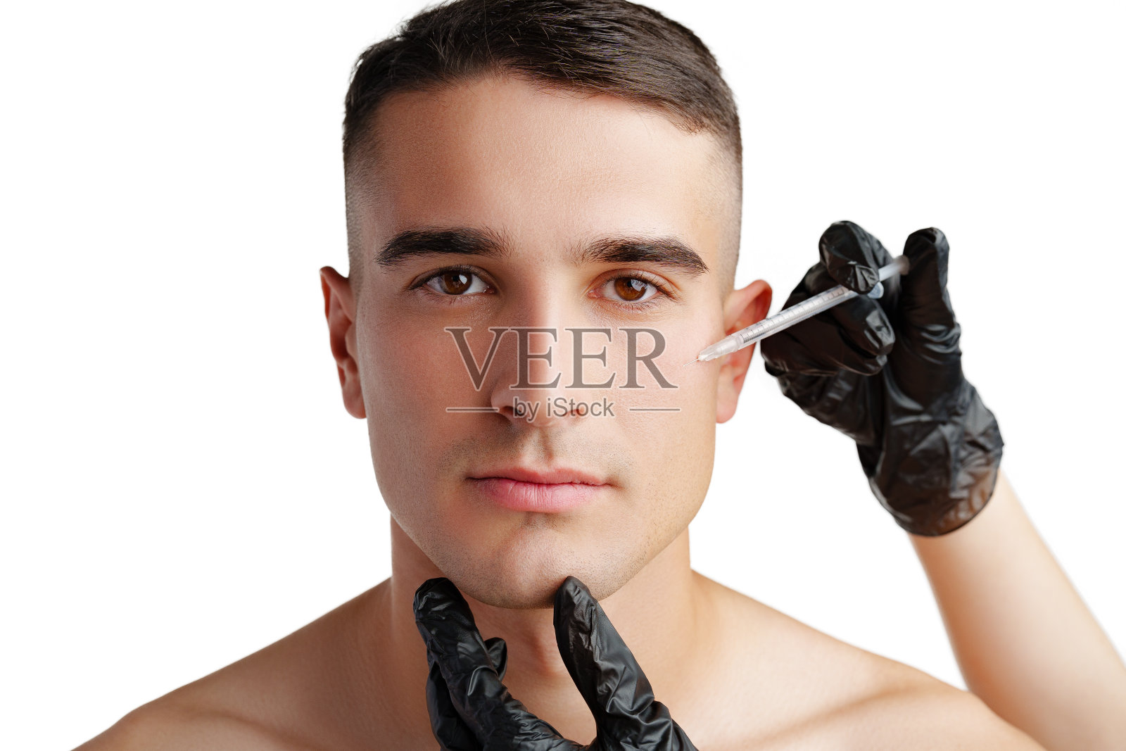 英俊的年轻人的脸和美容师的手用注射器在脸上注射化妆品照片摄影图片