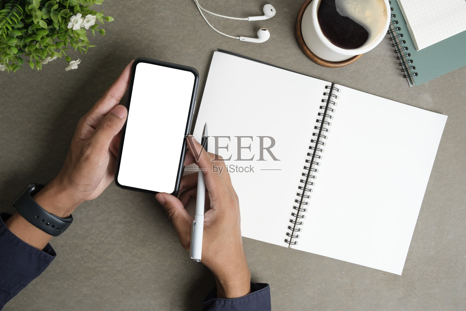 上图是一个人在创意工作空间使用手机。为您的广告设计空白屏幕。照片摄影图片