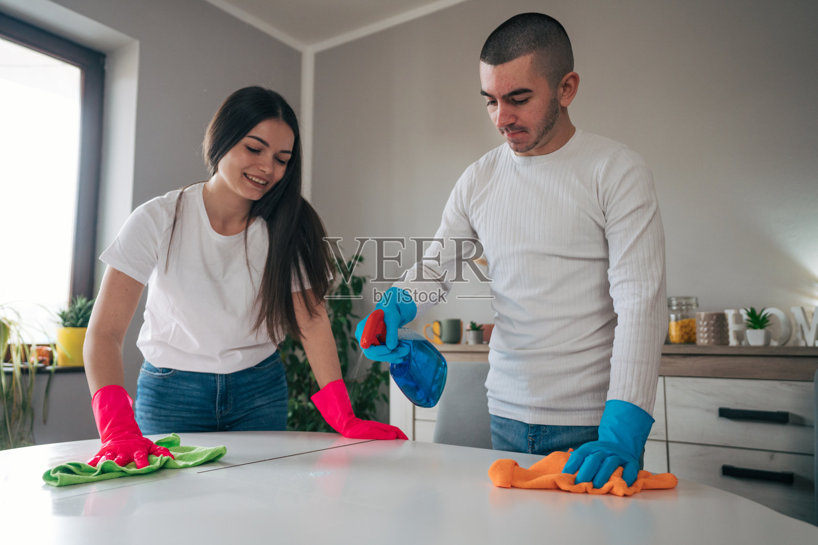 一对年轻夫妇负责公寓的清洁。照片摄影图片