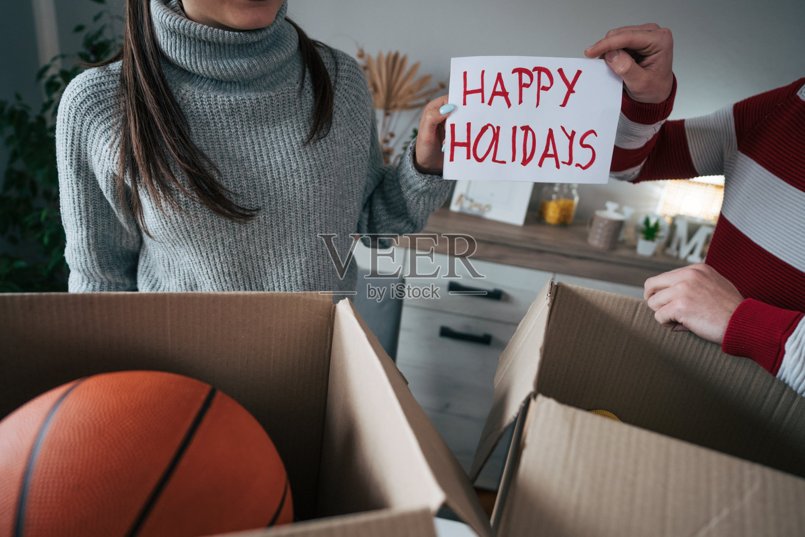 一对年轻夫妇聚在一起寻找慈善物品。他们举着“节日快乐”的牌子照片摄影图片