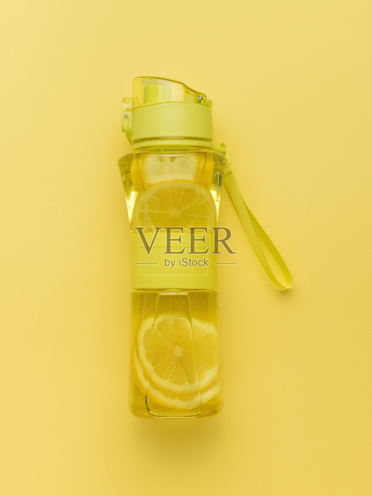 黄色背景上训练用的一瓶水和柠檬。照片摄影图片