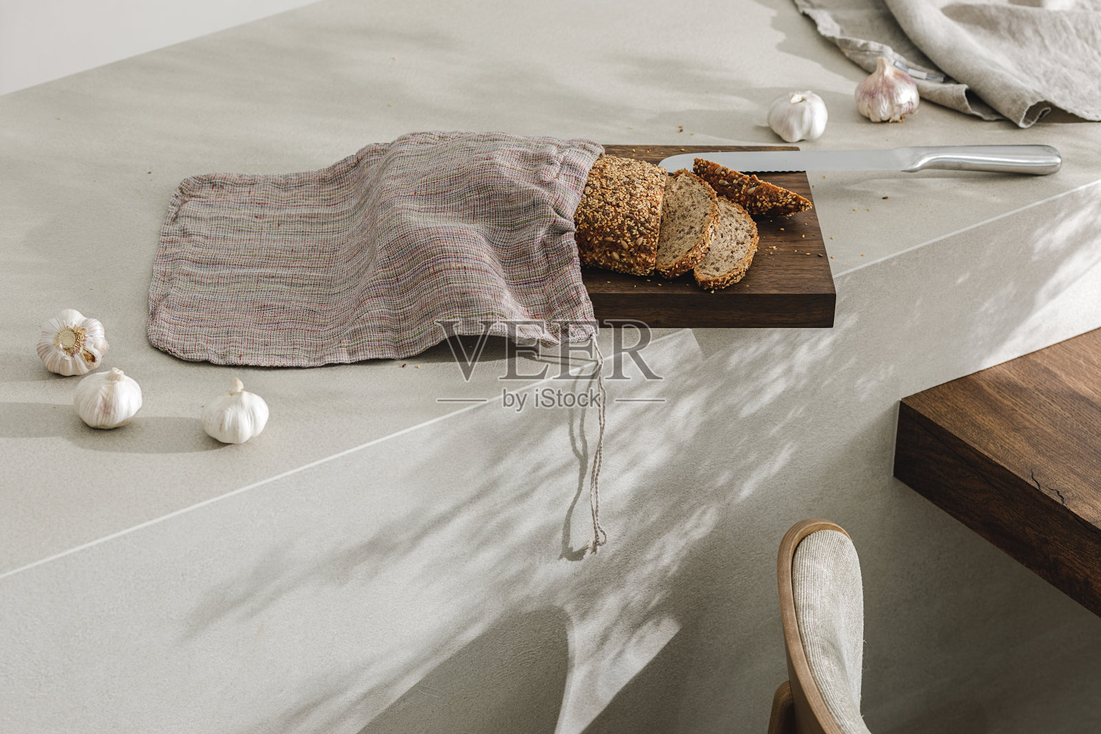切片面包装在麻袋里,放在木板上,大蒜和不锈钢厨刀。厨房美学概念照片摄影图片