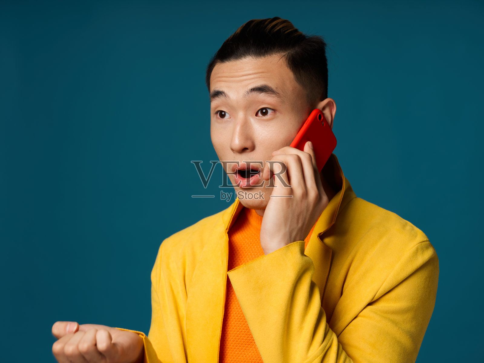 惊讶的男人在蓝色背景下打电话,用手做手势照片摄影图片