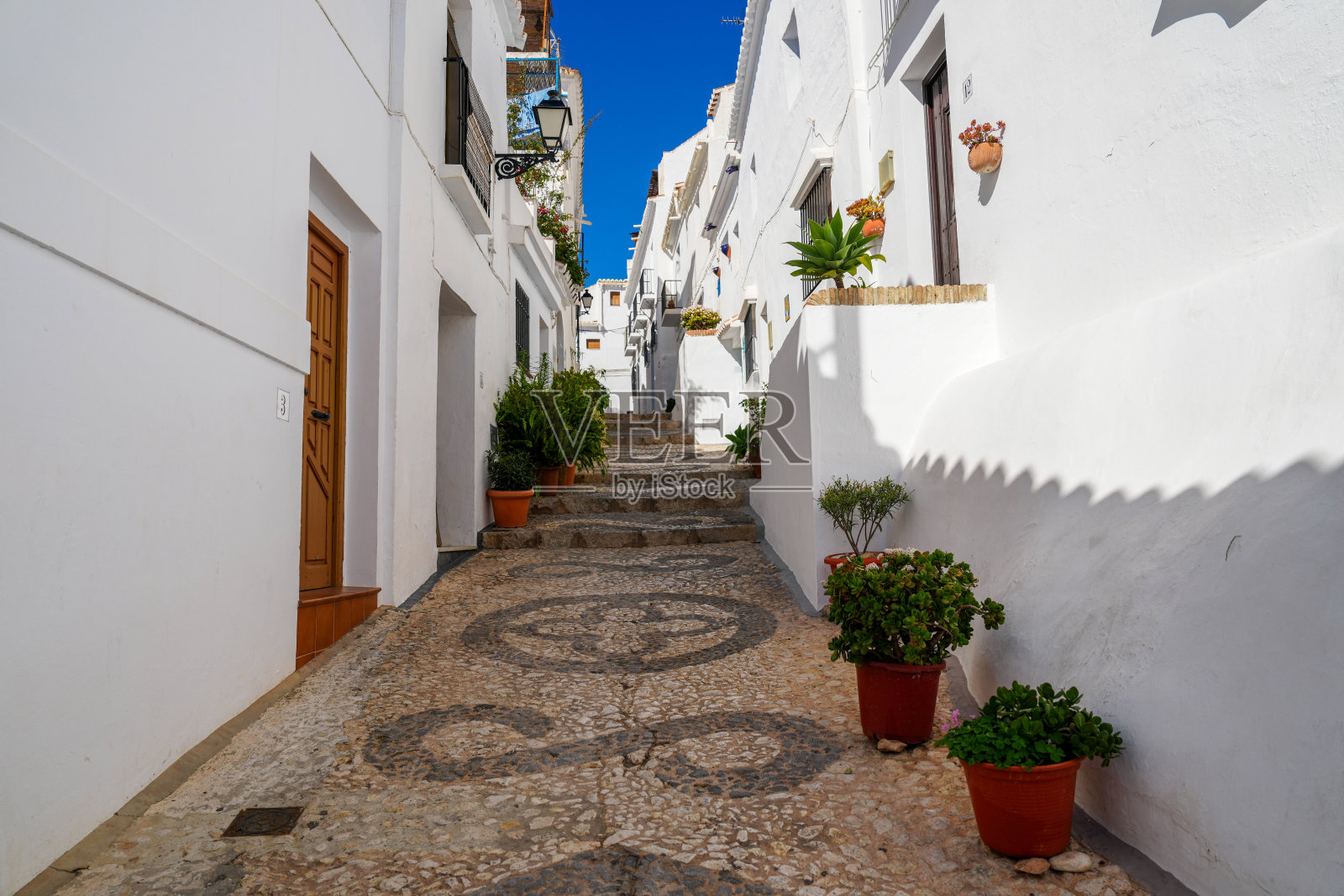 西班牙弗里吉利亚纳白色山坡村庄狭窄街道上五颜六色的花盆照片摄影图片