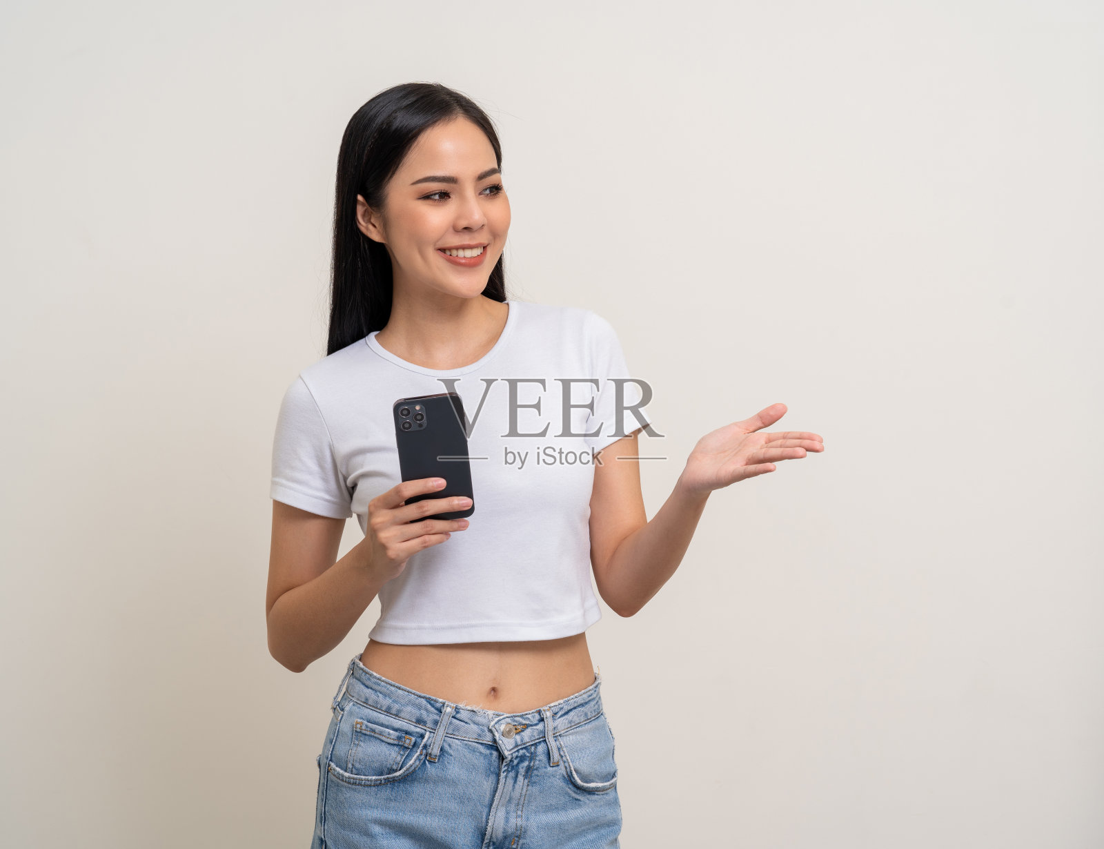 有吸引力的漂亮年轻的亚洲女人用手机站在孤立的白色背景。快乐兴奋美丽年轻的亚洲购物网上支付与手机。用智能手机玩游戏照片摄影图片