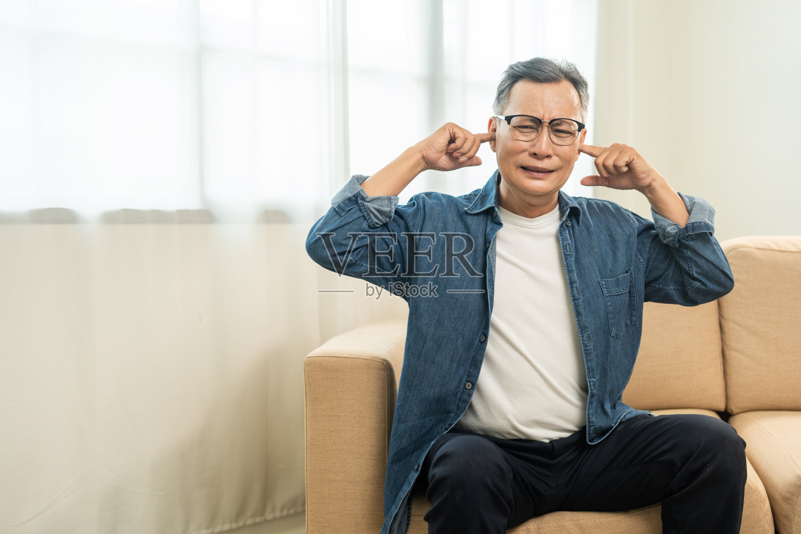 英俊的亚洲成熟老人压力和沮丧,用手捂住耳朵,因为大声的噪音,邻居打扰了家里。恼人的噪音、声音污染。亚洲老头堵着耳朵照片摄影图片