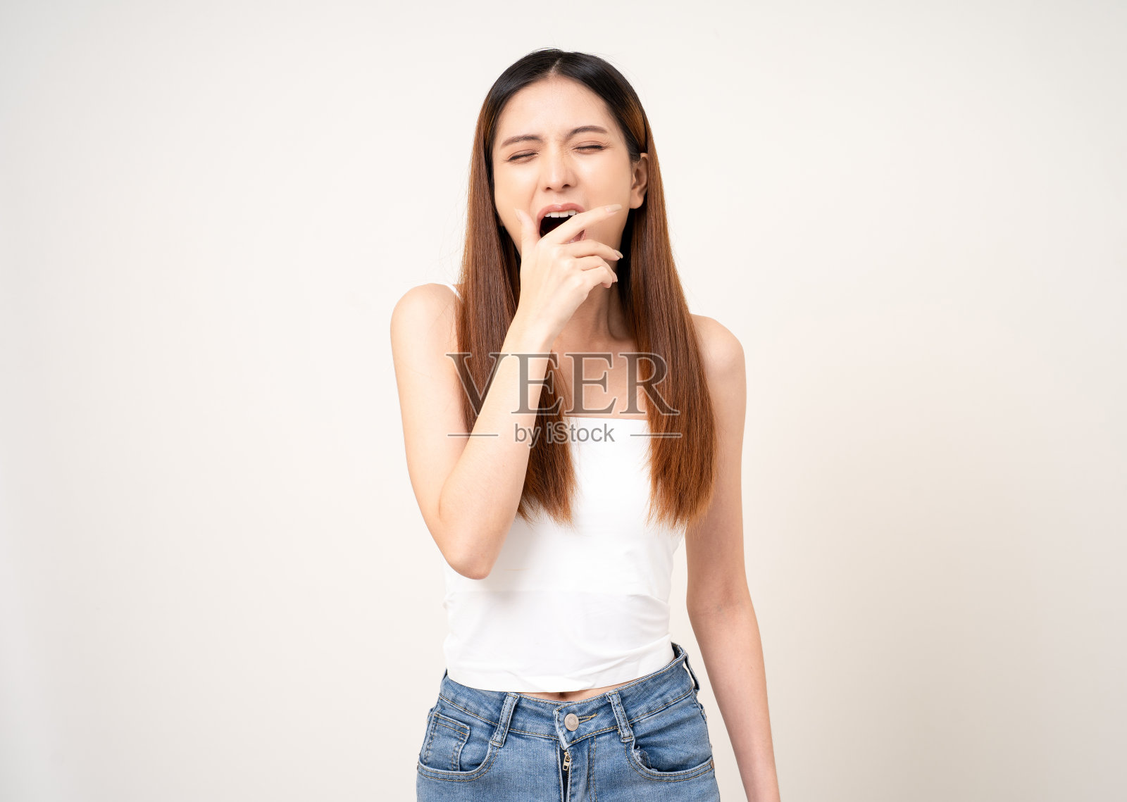 打哈欠的年轻亚洲女人她晚上不睡觉。休息不够。昏睡的雌性在孤立的白色背景上。用手捂住嘴。照片摄影图片