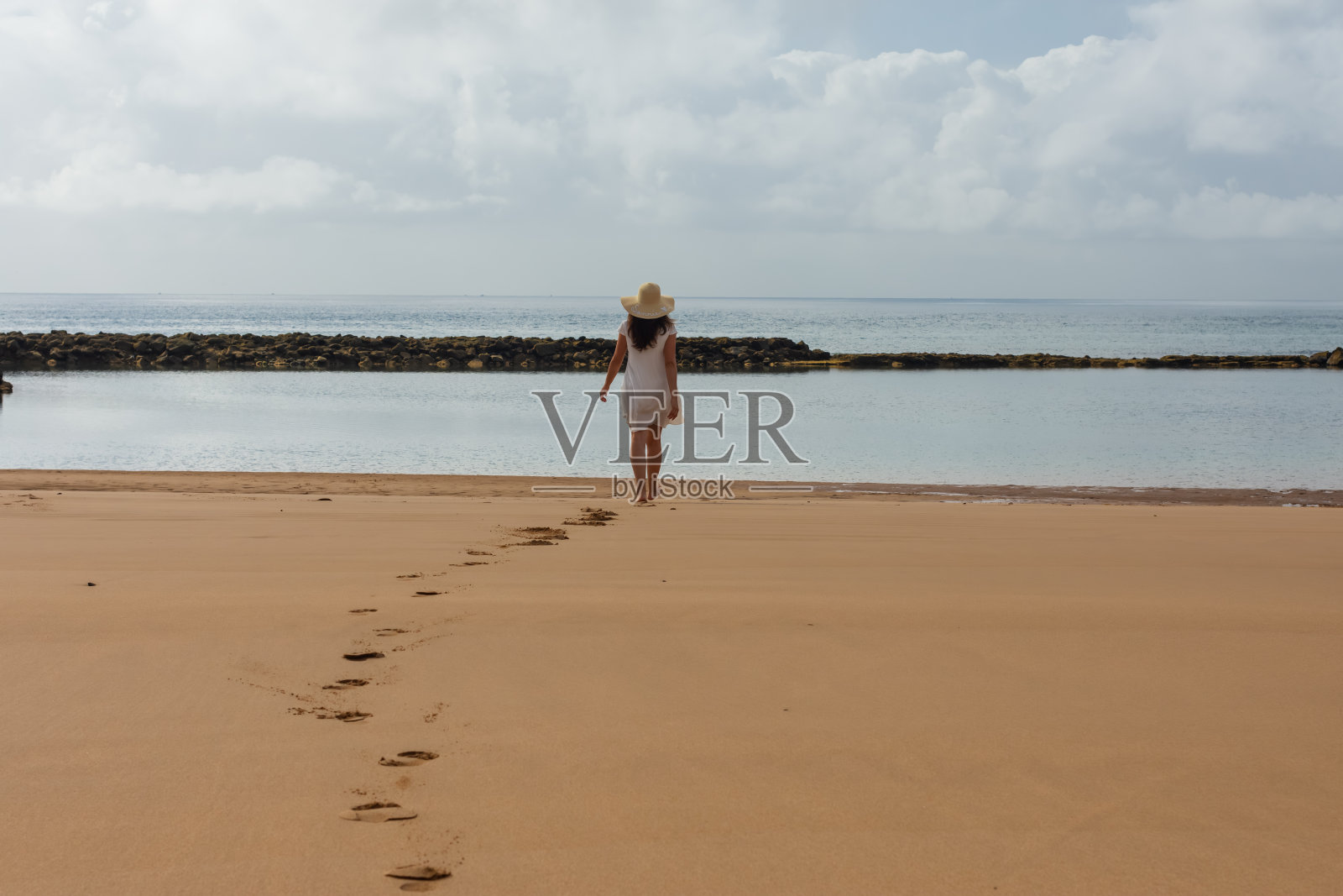 一个戴帽子的女人朝海滩走去照片摄影图片
