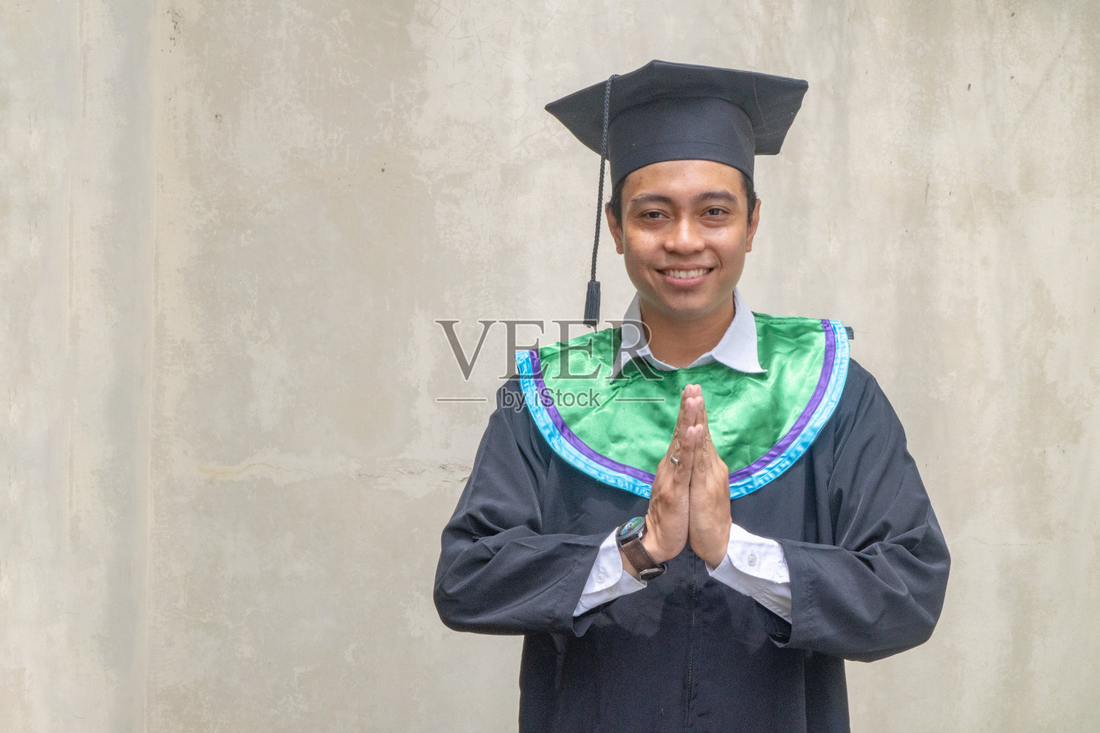 年轻的印尼小伙在毕业时摆出打招呼的姿势。照片摄影图片