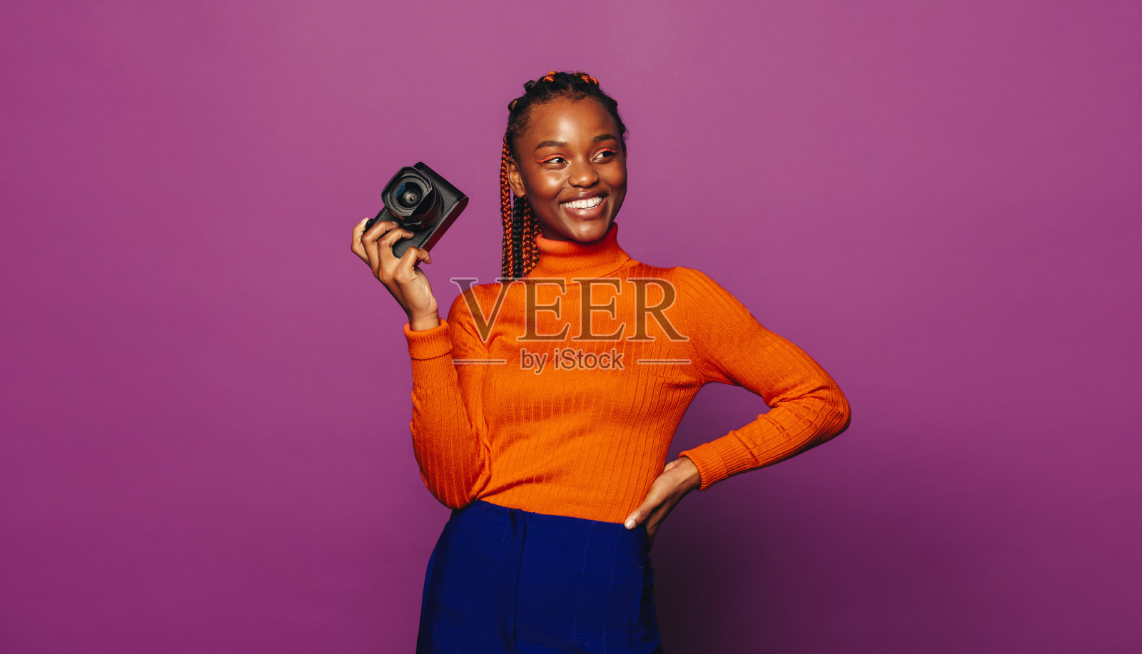 开朗的扎着辫子的女人微笑着在充满活力的紫色背景上拍照照片摄影图片
